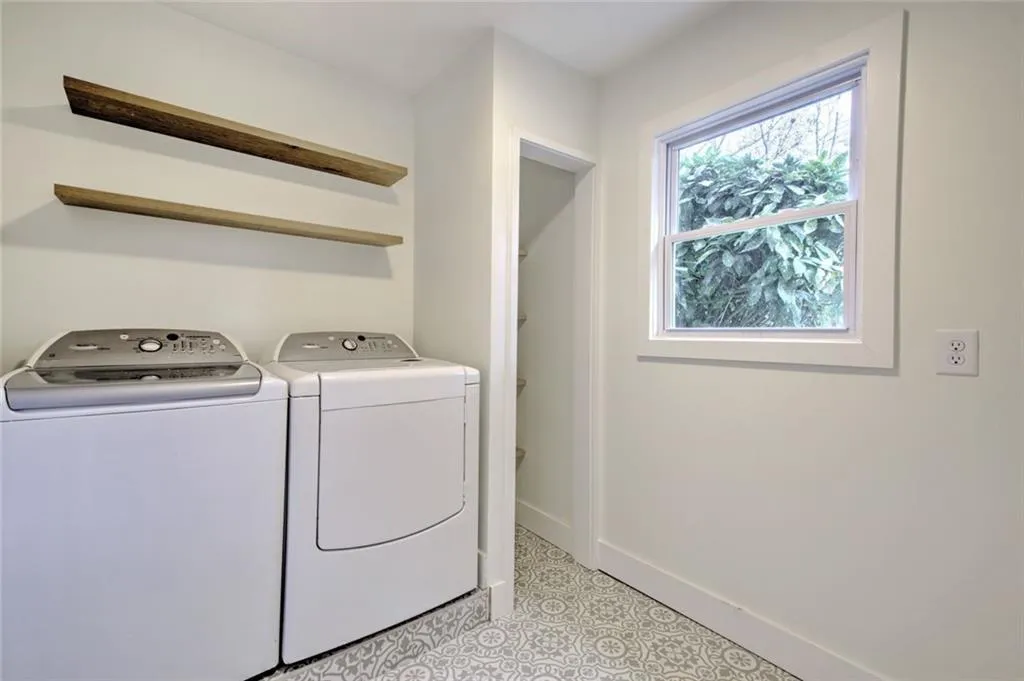 Laundry room with washer and clothes dryer and light flooring