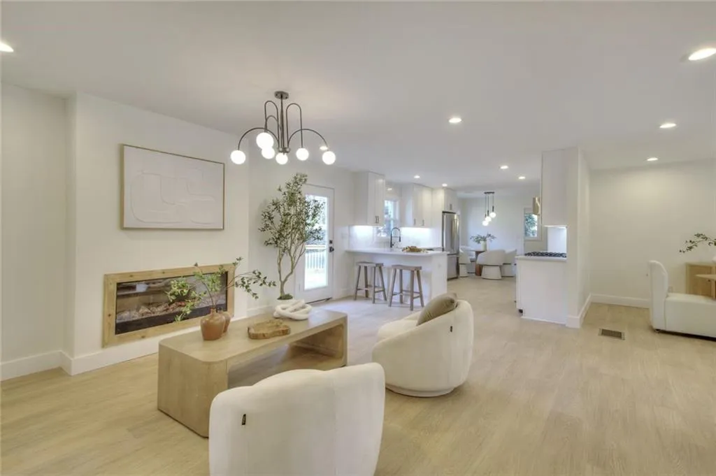 Living area with recessed lighting, light wood-type flooring, a chandelier, and a glass covered fireplace