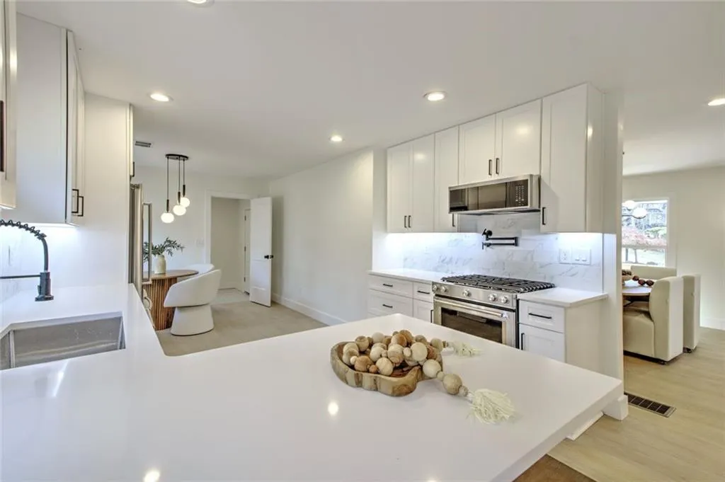 Kitchen with white cabinets, stainless steel appliances, a peninsula, recessed lighting, and pendant lighting