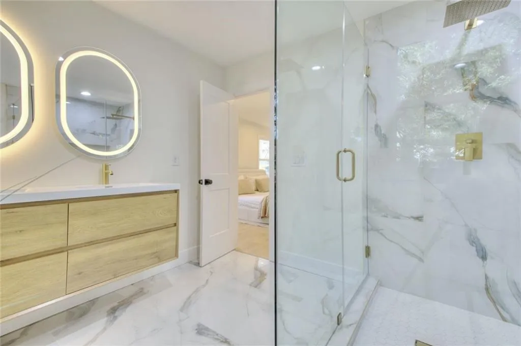 Ensuite bathroom with vanity, light marble finish flooring, and a marble finish shower