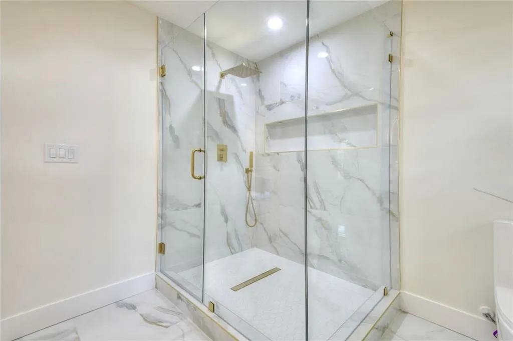 Full bathroom with marble tiled floors and a marble finish shower