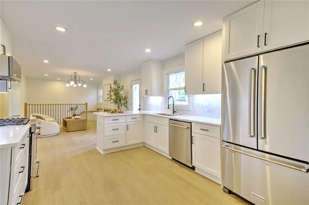 Kitchen with high quality appliances, white cabinets, a peninsula, open floor plan, and decorative backsplash