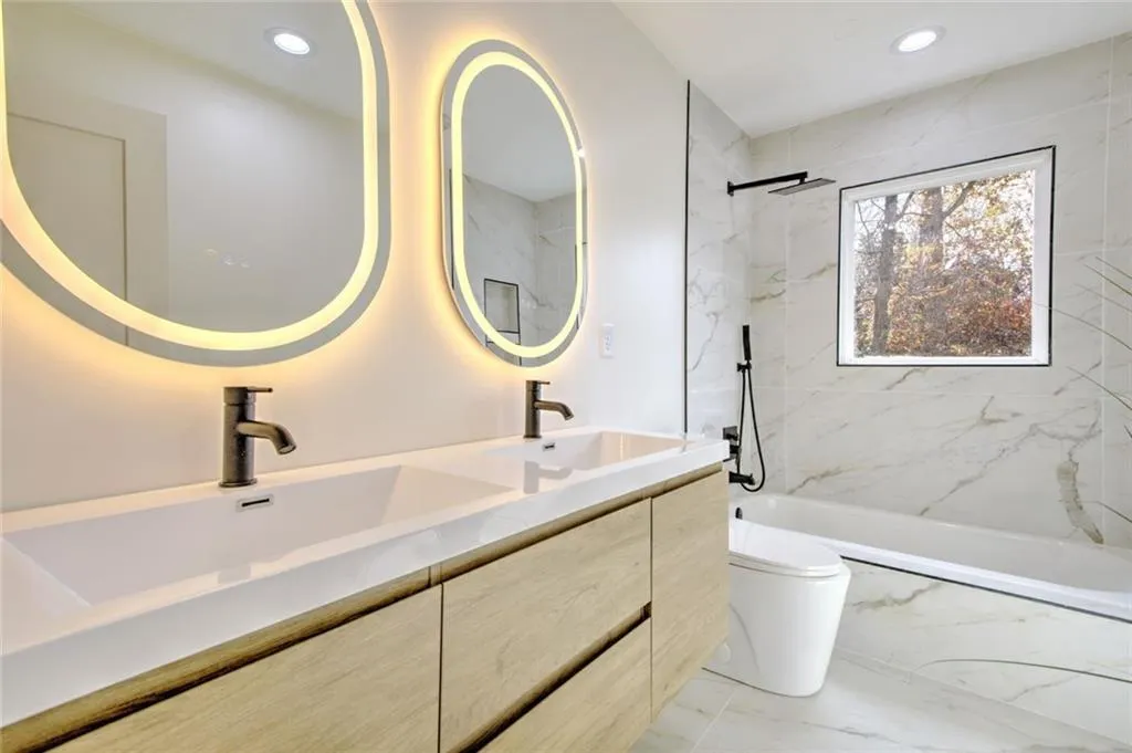 Full bathroom featuring double vanity, light marble finish floors, recessed lighting, and a combined bath / shower with marble appearance