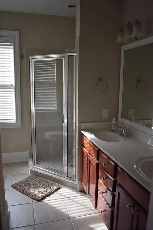 Bathroom with walk in shower, dual vanity, and tile floors