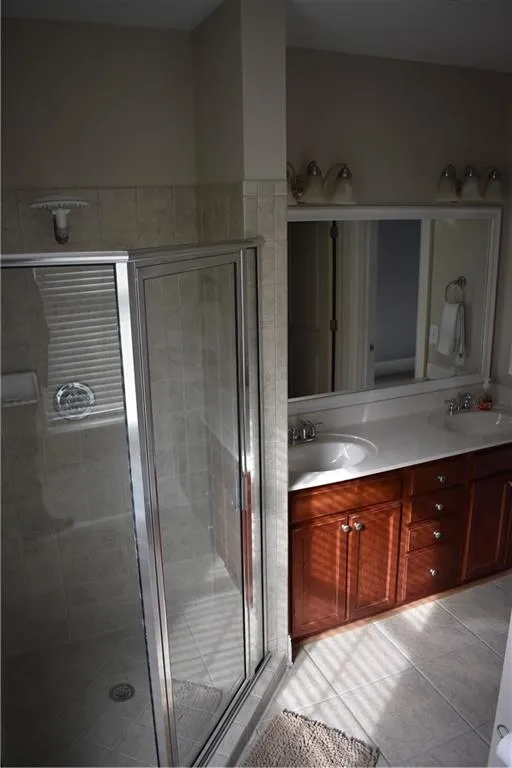 Bathroom with vanity with extensive cabinet space, tile floors, double sink, and walk in shower