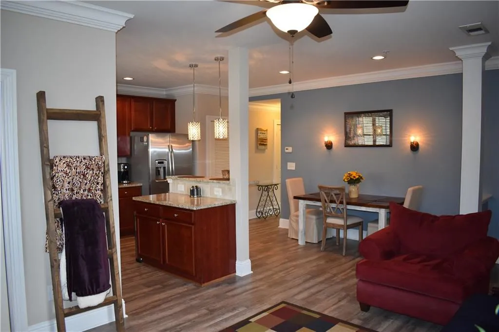 Kitchen featuring ceiling fan, dark hardwood / wood-style floors, decorative light fixtures, stainless steel refrigerator with ice dispenser, and light stone countertops