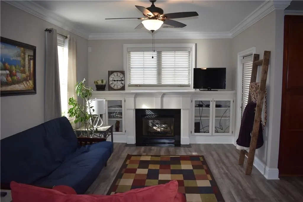 Living room featuring dark hardwood / wood-style flooring, crown molding, and ceiling fan