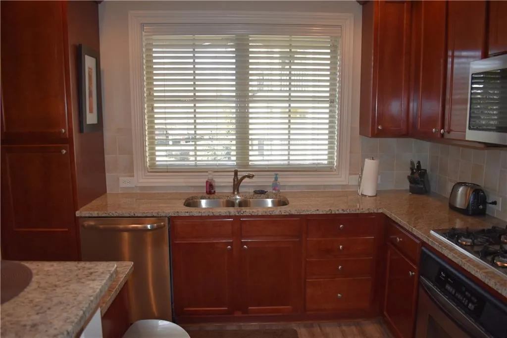 Kitchen with appliances with stainless steel finishes, a wealth of natural light, and sink