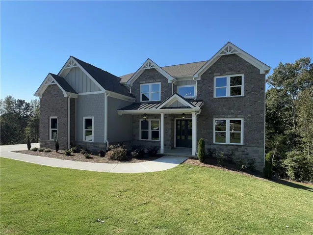 Craftsman-style home featuring a front yard, brick siding, stone siding, and board and batten siding
