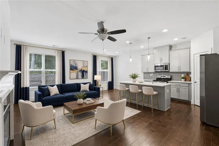 Virtually Staged - Open-concept living area featuring wood-finish flooring, a ceiling fan, and a kitchen with an island, pendant lighting, and stainless steel appliances