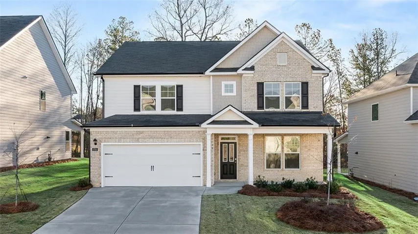 View of front of house with driveway, covered porch, a front lawn, brick siding, and an attached garage