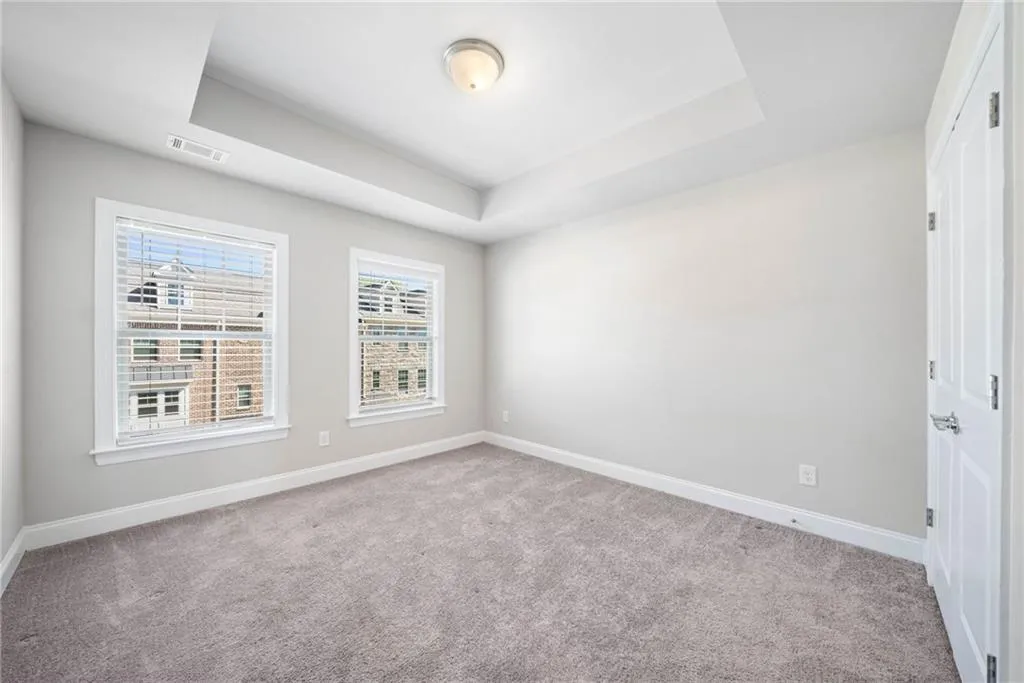 Empty room featuring a raised ceiling and light colored carpet