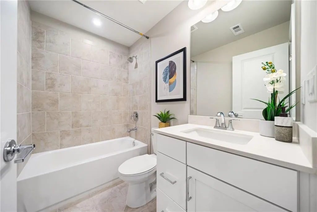 Bathroom with tub / shower combination, vanity, and light tile patterned flooring