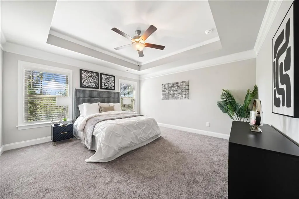 Bedroom featuring crown molding, carpet flooring, a tray ceiling, and multiple windows