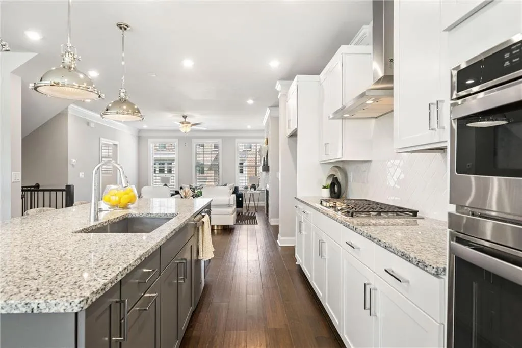 Kitchen featuring appliances with stainless steel finishes, white cabinetry, dark wood finished floors, pendant lighting, and wall chimney exhaust hood