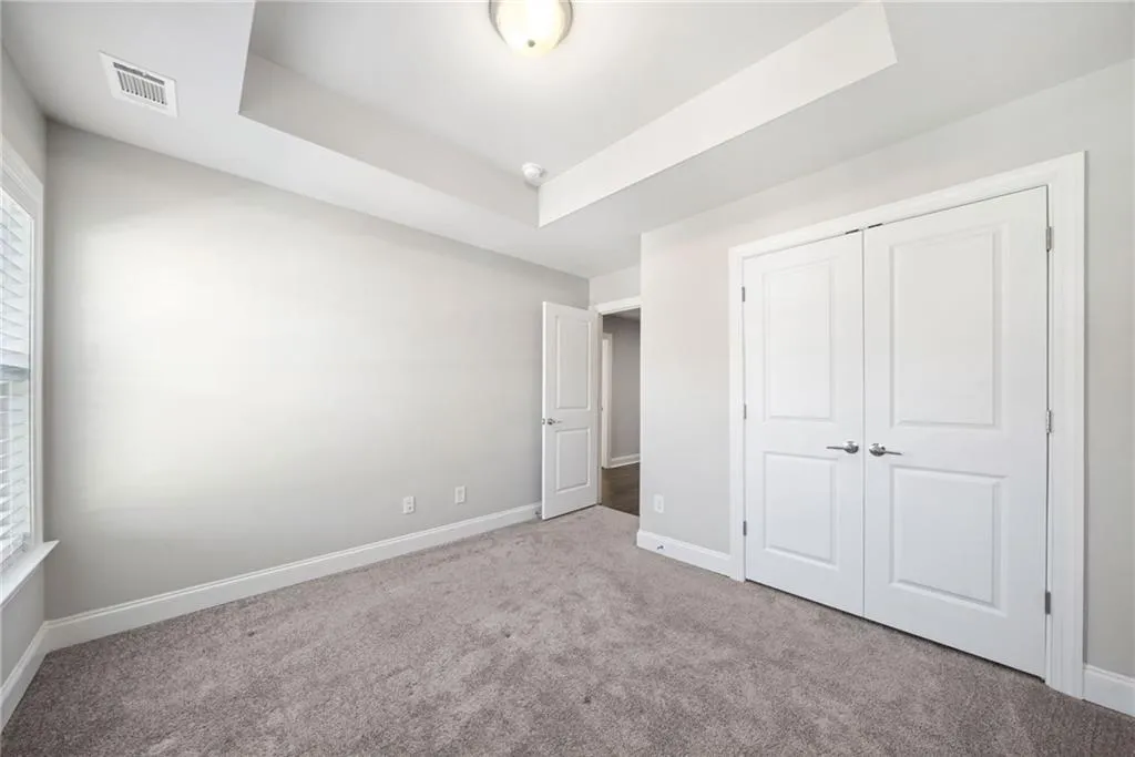 Unfurnished bedroom with a raised ceiling, carpet, and a closet
