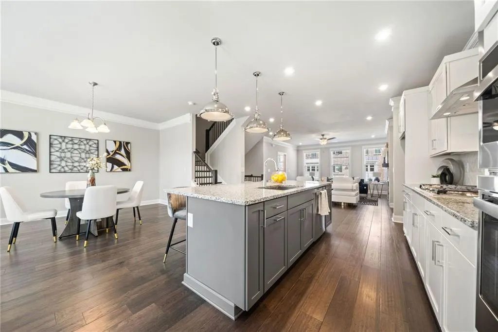 Kitchen with gray cabinets, white cabinetry, crown molding, a kitchen island with sink, and recessed lighting