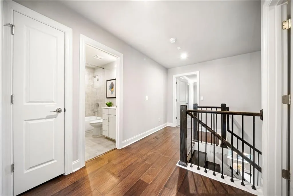 Corridor with an upstairs landing, dark wood-type flooring, and recessed lighting