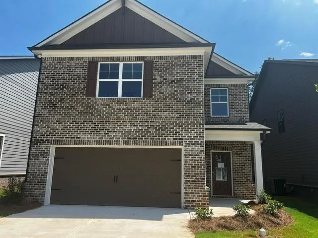 Two-story brick exterior featuring a two-car garage, covered entry porch, and decorative window shutters