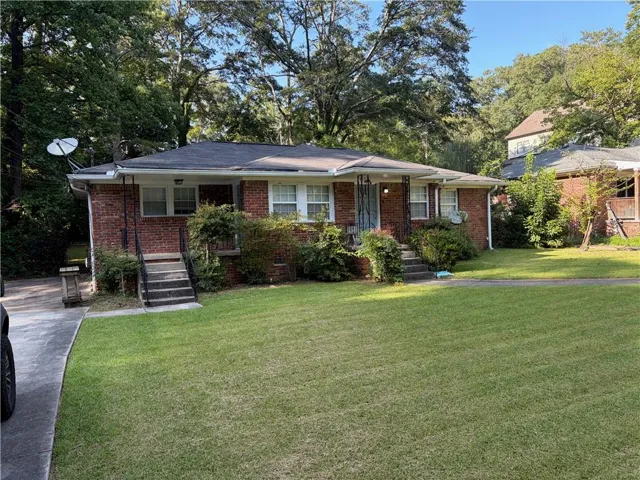 Brick exterior, gabled roof, dual front entryways with railings, expansive front lawn, and mature trees