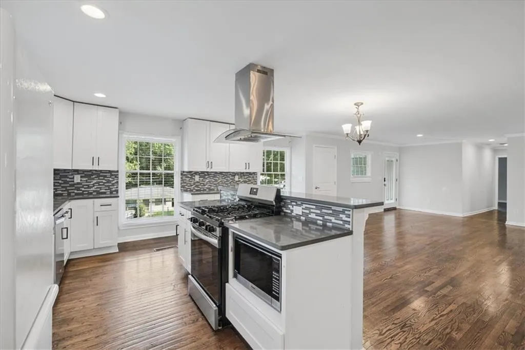 Kitchen featuring white cabinetry, stainless steel appliances, a mosaic tile backsplash, wood-finish flooring, and recessed lighting
