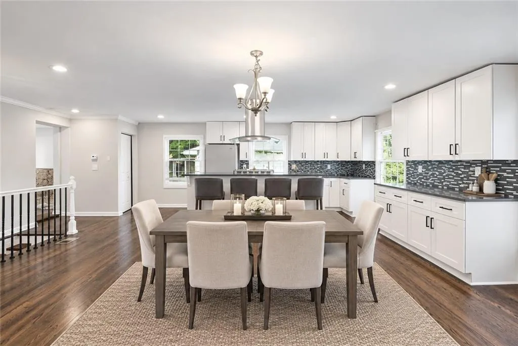 Open-concept dining area with wood-finish flooring, recessed lighting, and a modern chandelier