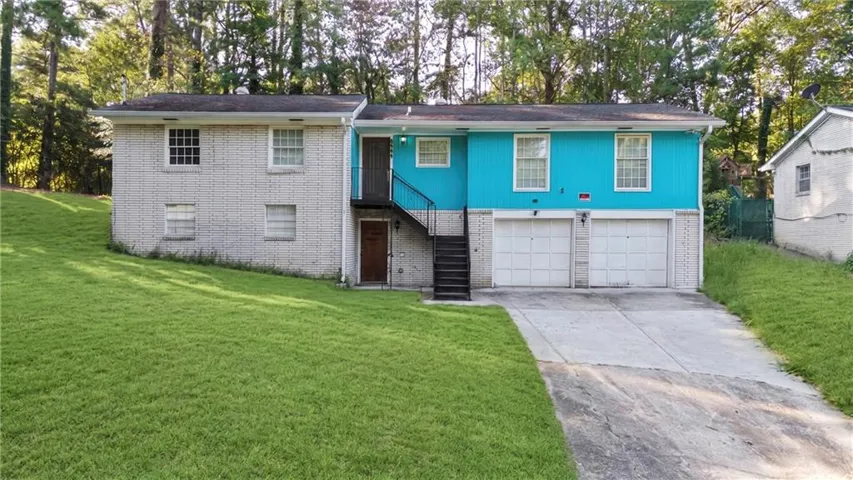 Split-level residence featuring a brick and siding exterior, dual garage doors, and a concrete driveway