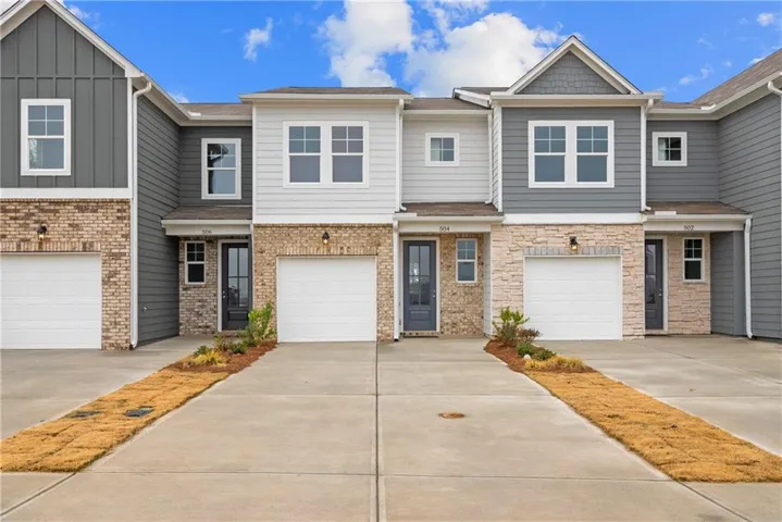 Modern townhome with attached garages, brick and stone veneer accents, and board and batten siding