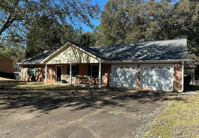 Brick exterior with a gabled roofline, featuring a two-car garage with panel doors and upper window inserts