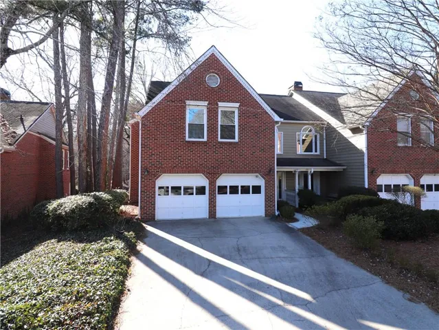 View of front of house with an attached garage, brick siding, driveway, and a porch