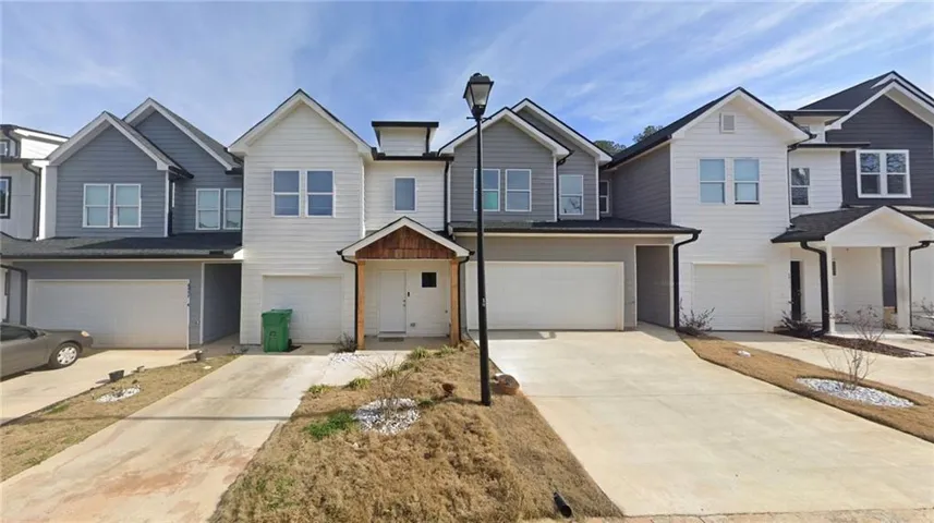 Contemporary townhome exterior featuring white and gray siding, contrasting dark rooflines, and individual single-car garages