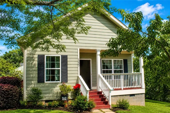 Light green horizontal siding exterior with a welcoming red-painted front porch