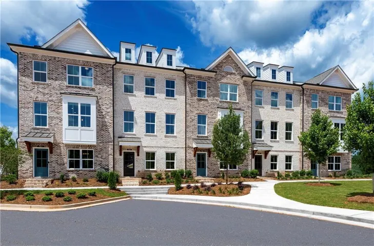 Brick facade with dormer windows, covered entryways, and professional landscaping