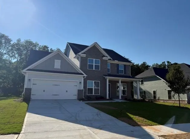 Two-story residence featuring a brick and siding facade, a two-car garage, and a covered front entry