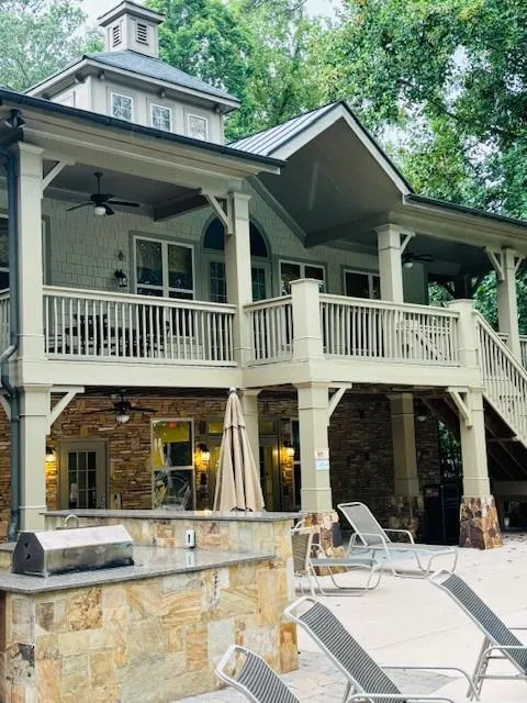 Clubhouse with stone siding, a patio, and a metal roof