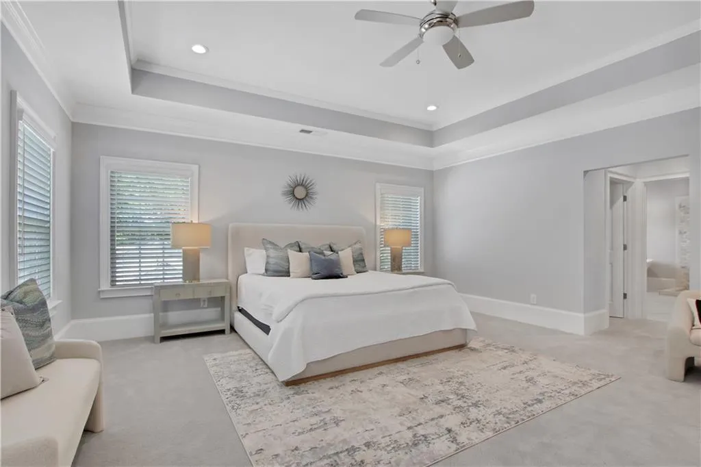 Bedroom with light colored carpet, ornamental molding, a raised ceiling, a ceiling fan, and recessed lighting