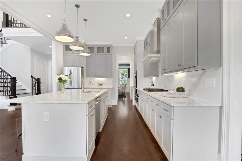 Kitchen with dark wood finished floors, recessed lighting, a center island with sink, appliances with stainless steel finishes, and wall chimney range hood