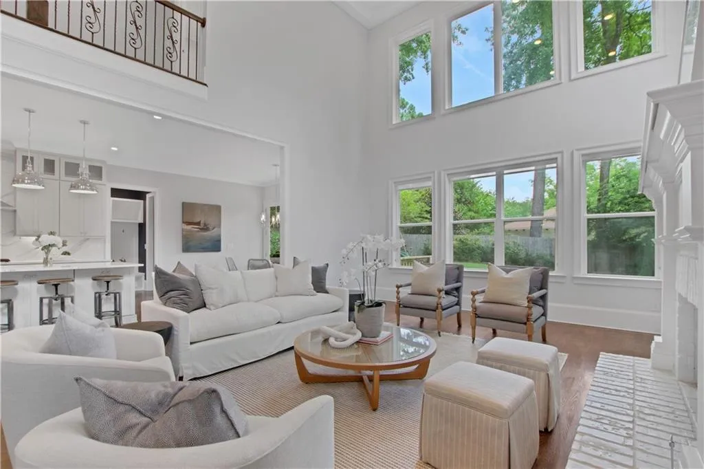 Living area with healthy amount of natural light, a towering ceiling, wood finished floors, and a fireplace