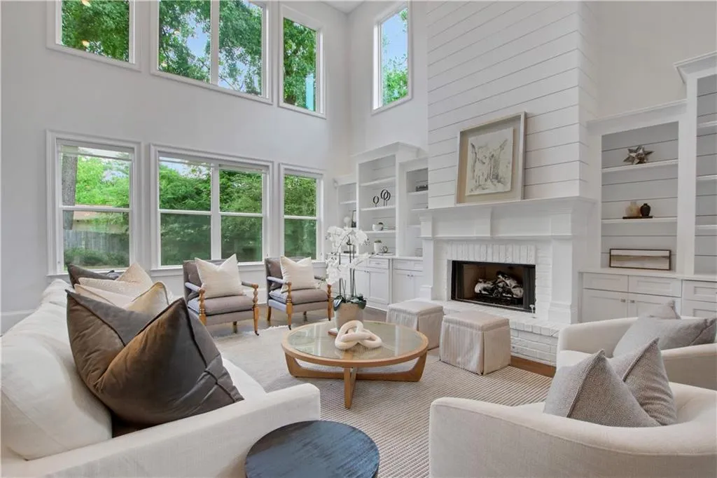 Living area with a towering ceiling, built in shelves, and a brick fireplace