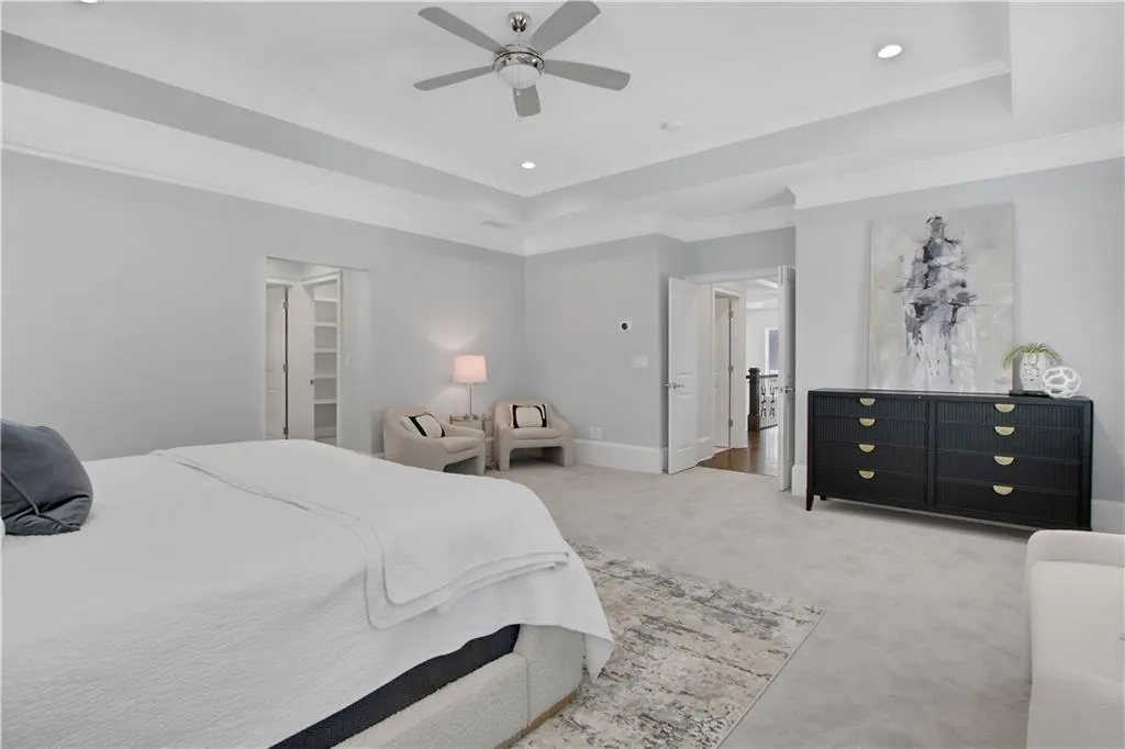 Bedroom featuring a tray ceiling, light colored carpet, ornamental molding, recessed lighting, and a ceiling fan