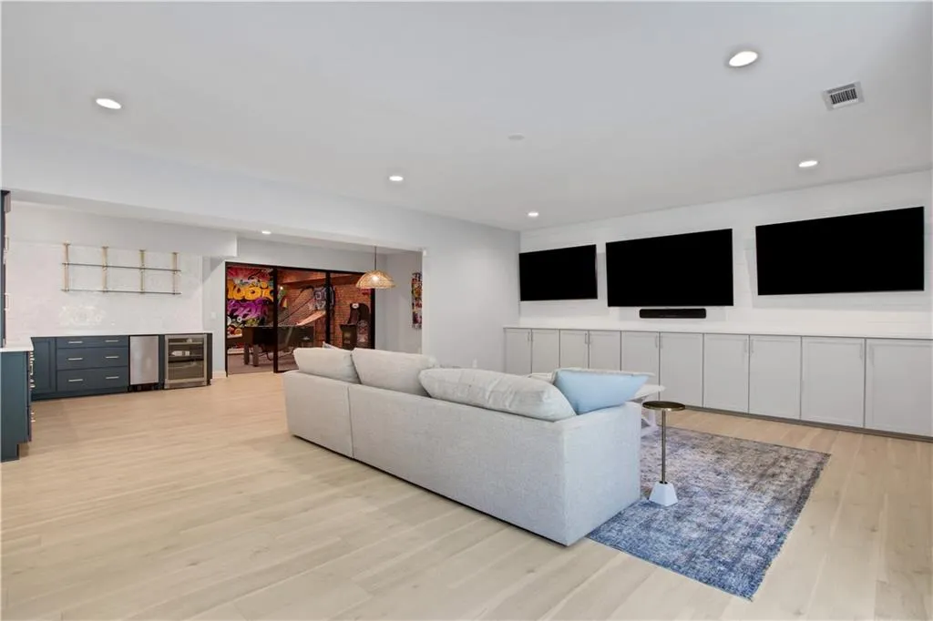 Living area featuring a bar, light wood-type flooring, recessed lighting, and beverage cooler