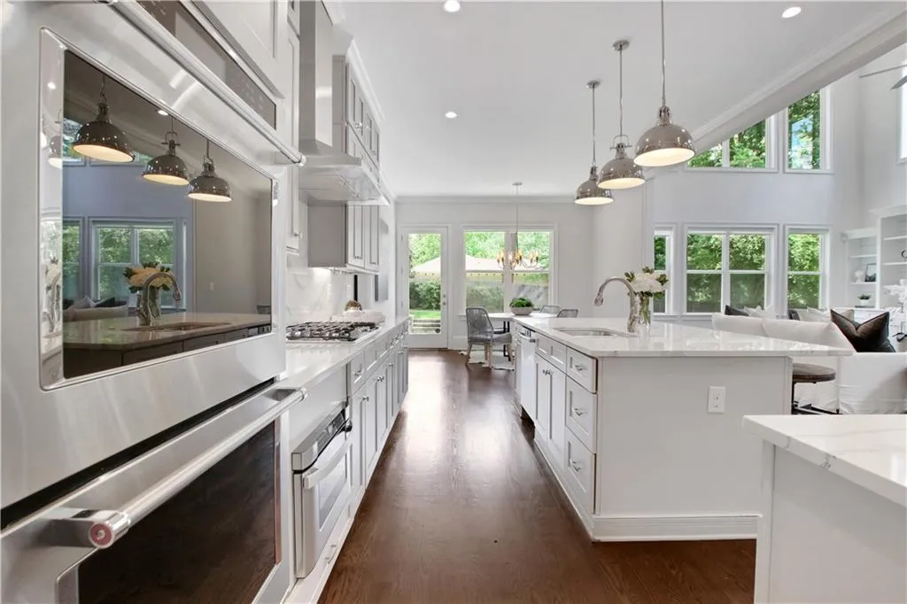 Kitchen featuring appliances with stainless steel finishes, white cabinets, dark wood-type flooring, light stone counters, and crown molding