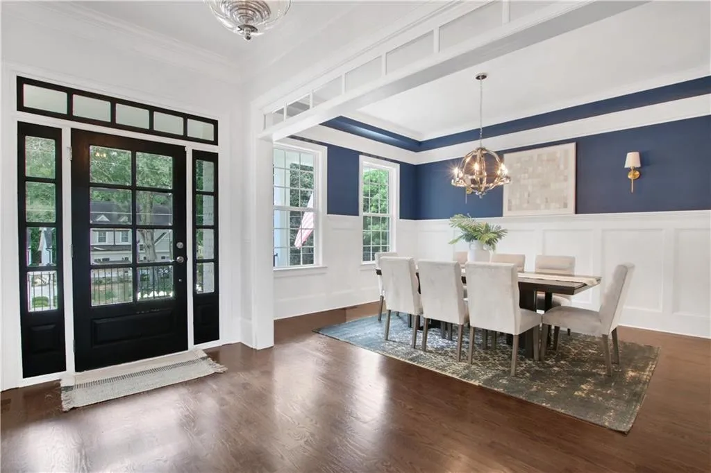 Dining room featuring a chandelier, a wainscoted wall, a decorative wall, crown molding, and wood finished floors