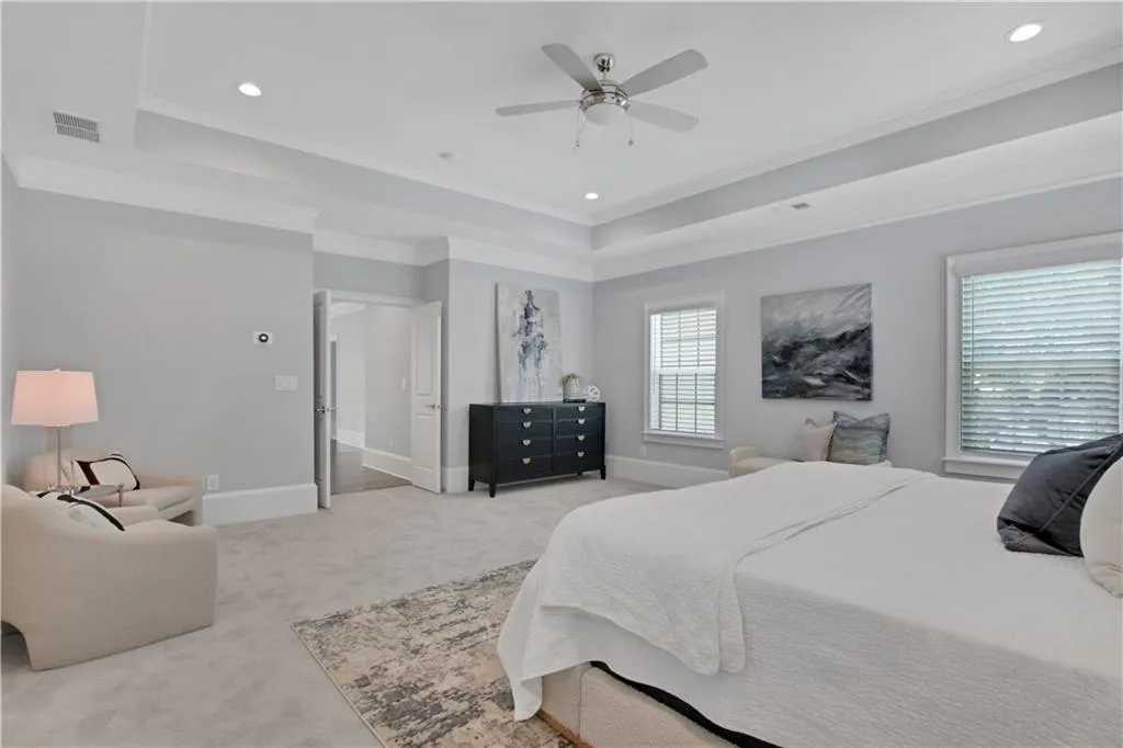 Bedroom featuring a raised ceiling, ornamental molding, light carpet, recessed lighting, and a ceiling fan