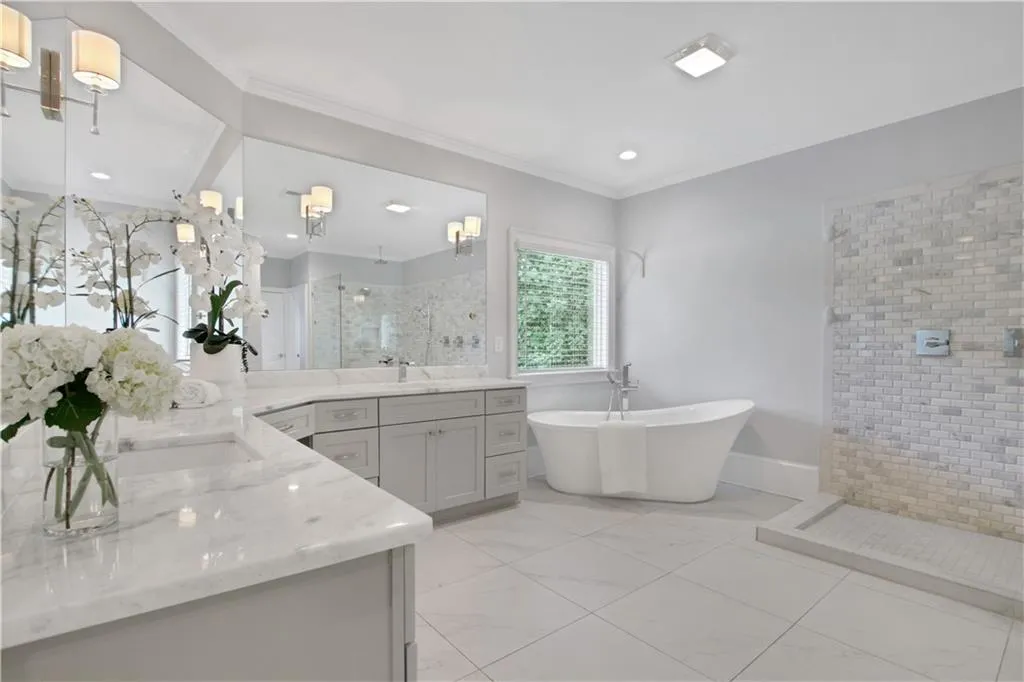 Bathroom featuring a shower stall, two vanities, a freestanding tub, ornamental molding, and recessed lighting