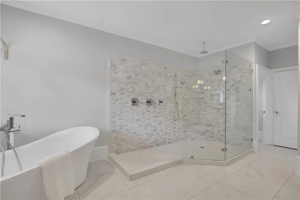 Bathroom featuring a stall shower, a freestanding bath, ornamental molding, marble finish floors, and recessed lighting