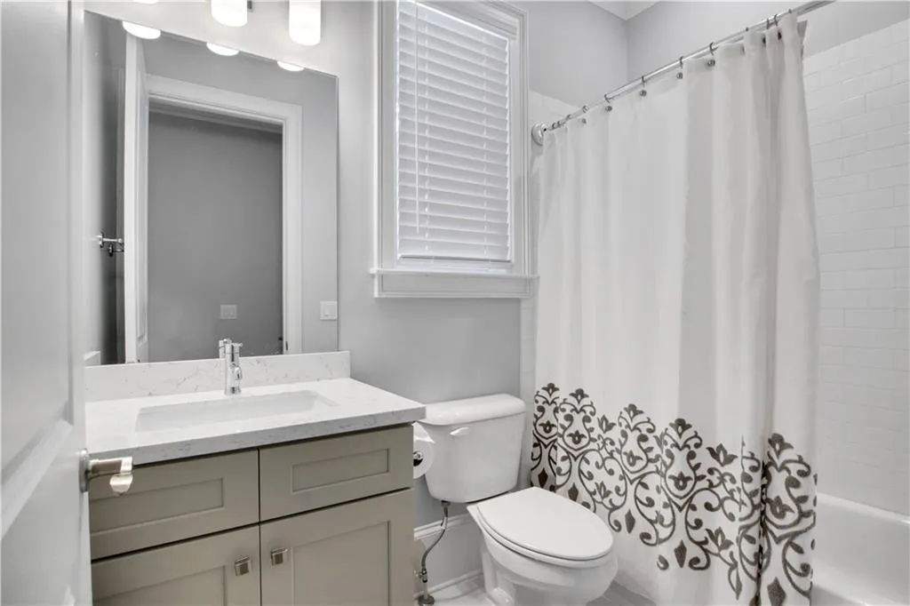 Main level Full bath featuring vanity and shower / bathtub combination with curtain