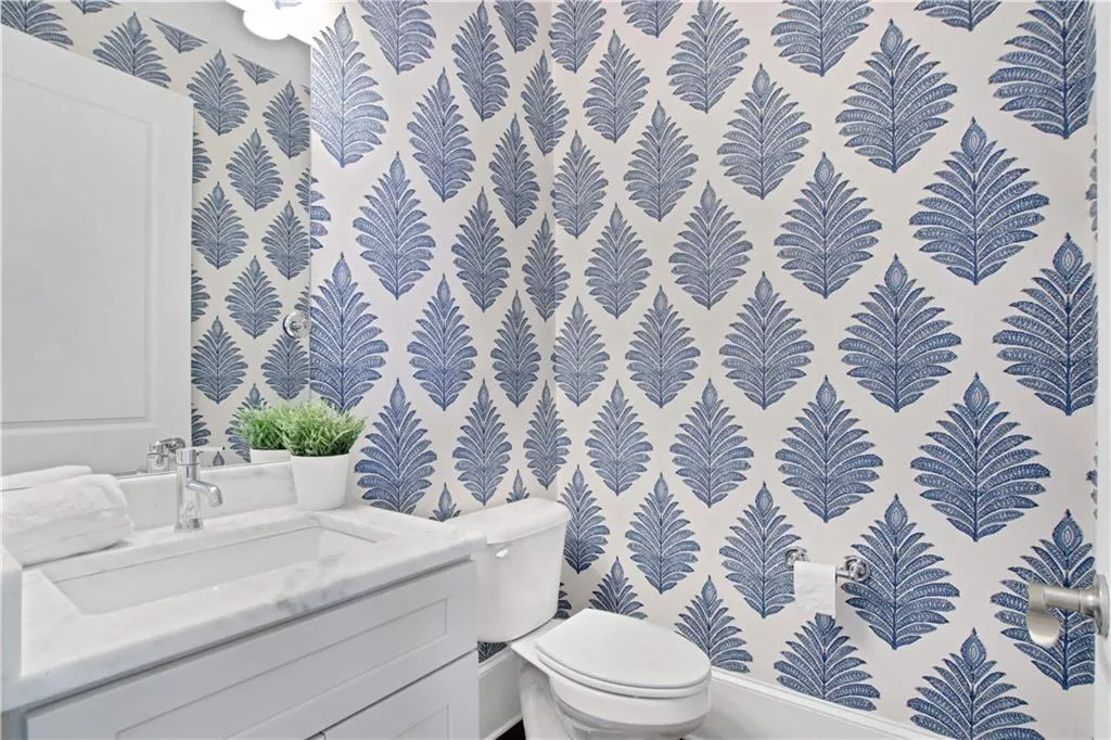 Half bath featuring wallpapered walls and vanity