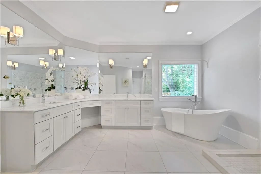 Full bath with vanity, a soaking tub, a stall shower, marble finish flooring, and crown molding