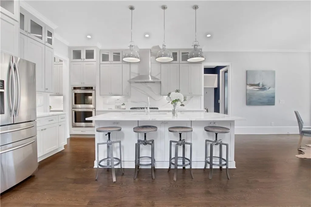 Kitchen with appliances with stainless steel finishes, crown molding, wall chimney exhaust hood, a kitchen breakfast bar, and a kitchen island with sink